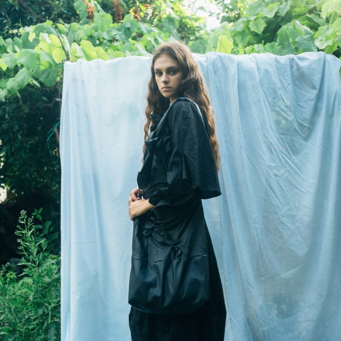 Black, loose-fitting, long-sleeved dress with a gathered waist and a slightly A-line silhouette.