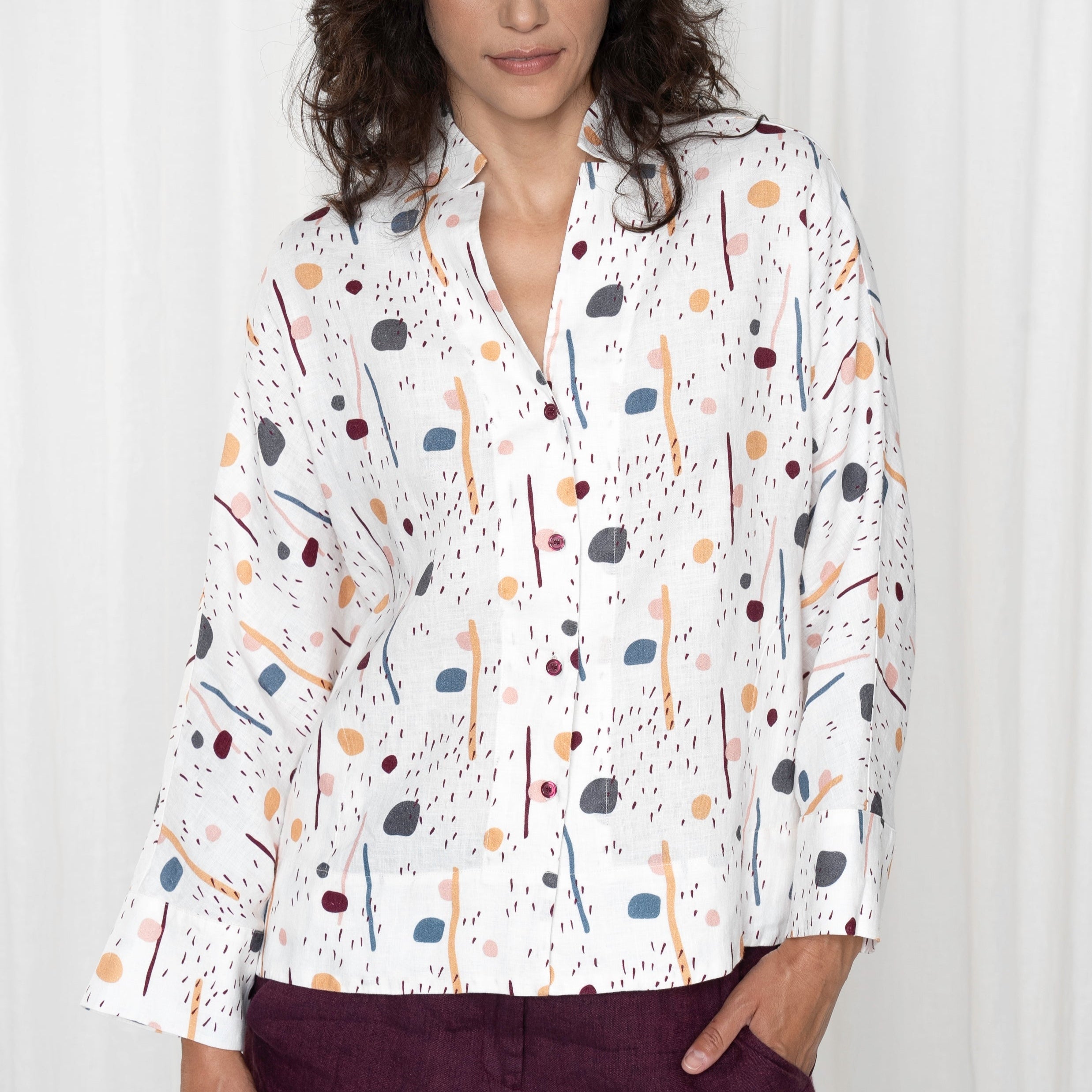 White linen shirt with an abstract print of colorful shapes and lines.  Three-quarter sleeves and button-down front.