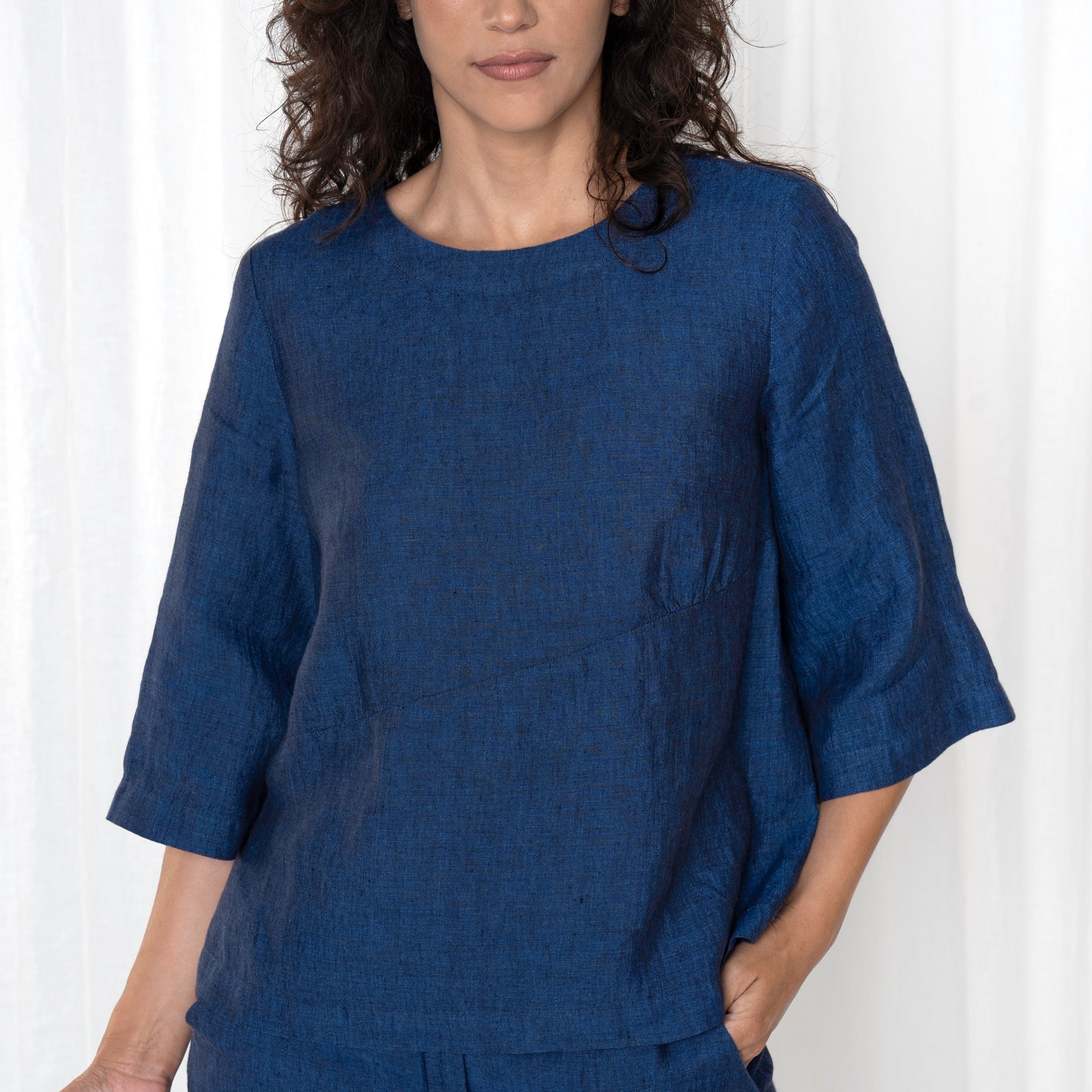 Dark blue linen top with three-quarter sleeves and a small pocket.  The top has a relaxed fit and a round neckline.
