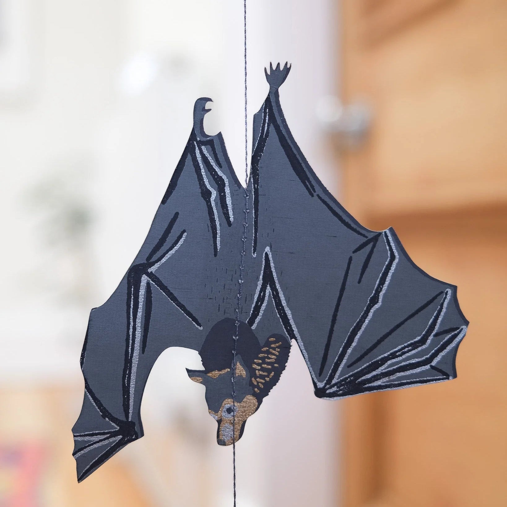 Decorative bat hanging on a string with a blurred background