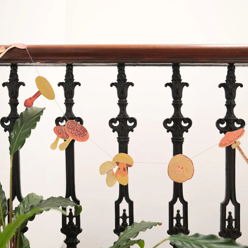 Mushroom garland with various colored and shaped paper mushrooms strung on twine.
