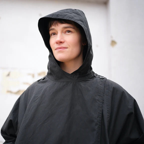 Black hooded poncho-style jacket with relaxed fit and subtle seam details.