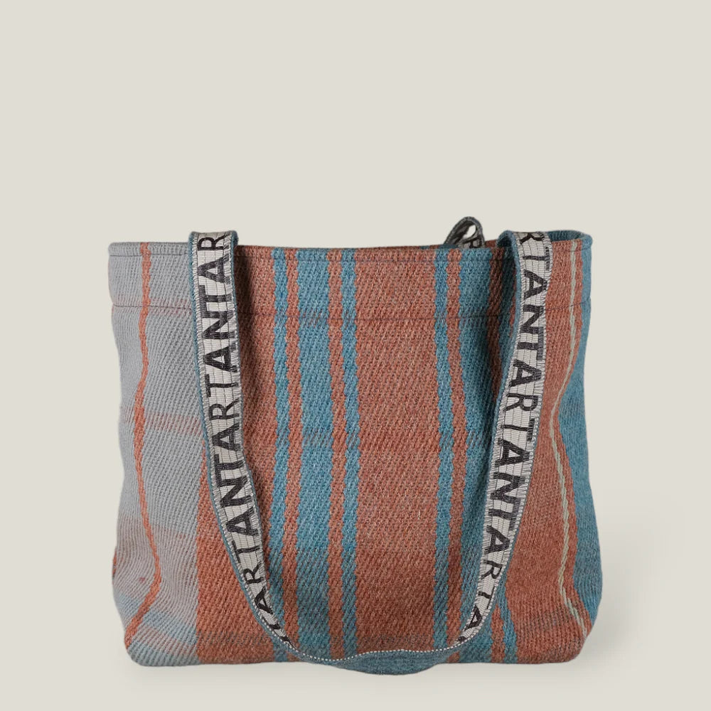 Woven tote bag with teal and terracotta striped pattern and logo-branded shoulder straps.
