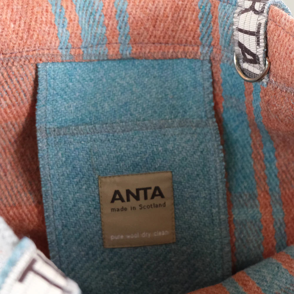 Interior view of an ANTA wool tote bag, teal lining with coral and teal striped exterior, showing a label indicating "made