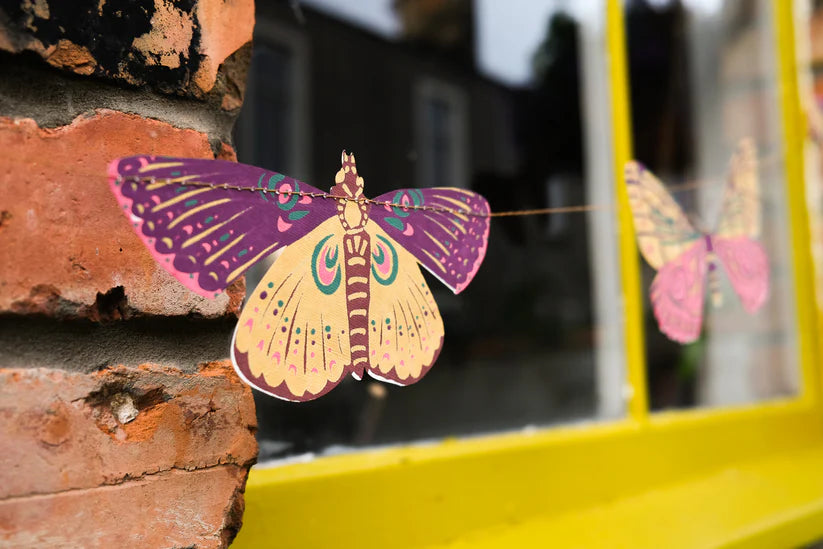 Paper butterfly garland with purple and yellow butterflies strung on a thin wire.