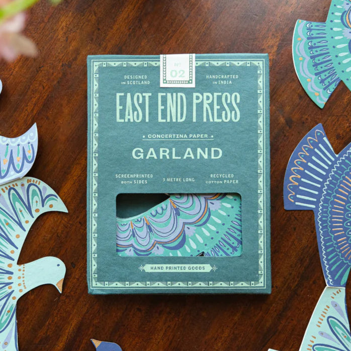 Pack of East End Press Garland on a wooden surface with decorative cutouts.