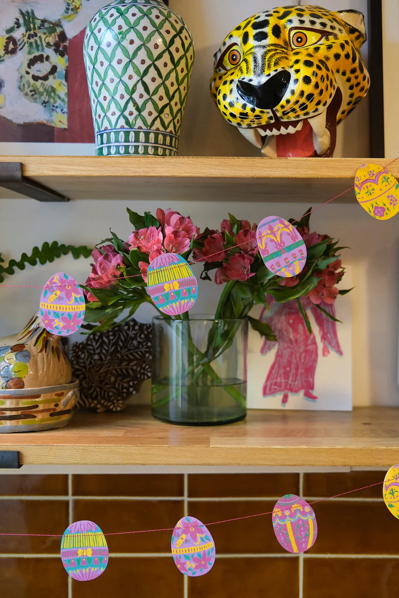 Decorative shelf with flowers, vases, and Easter-themed decorations.
