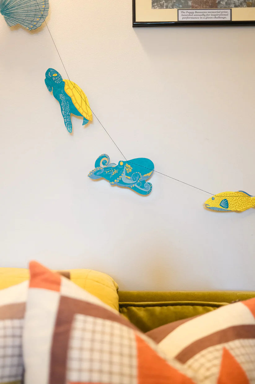Sea creature garland with a turtle, octopus, and fish.  Teal and yellow paper cutouts on string.
