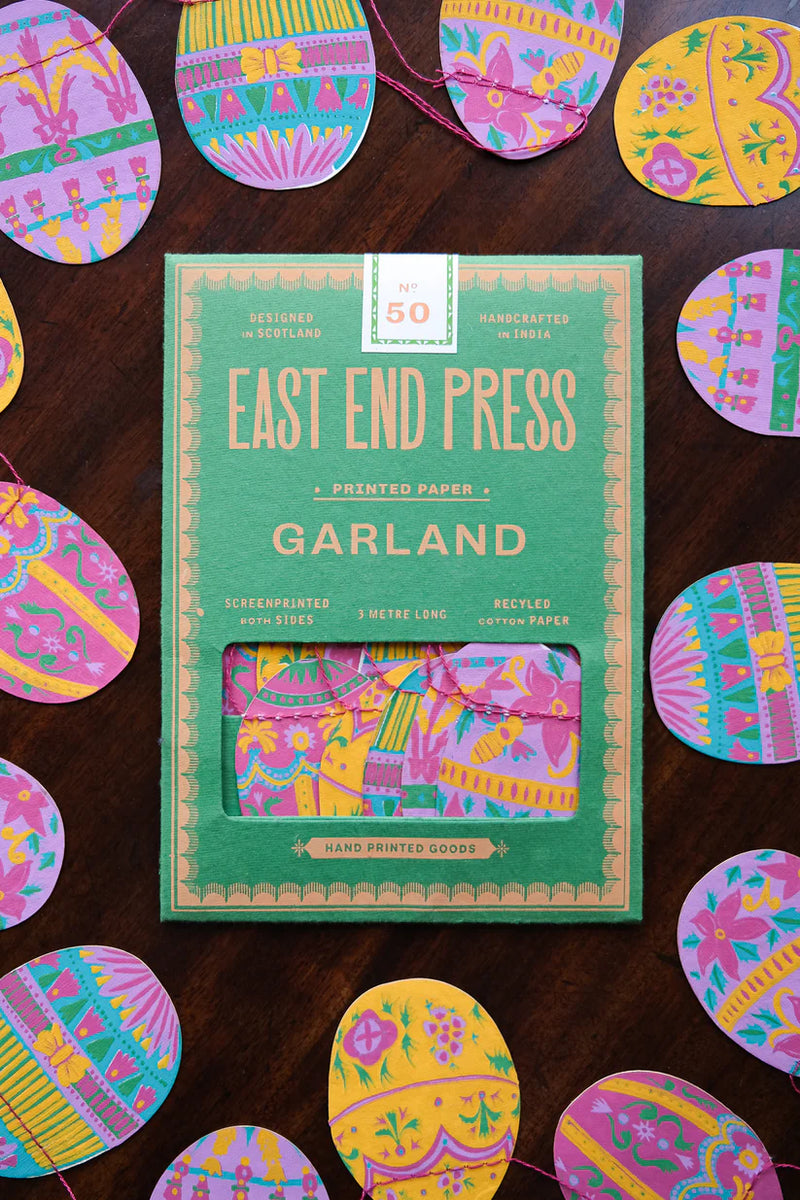 Packaging of East End Press Garland with colorful printed paper strips on a wooden surface.