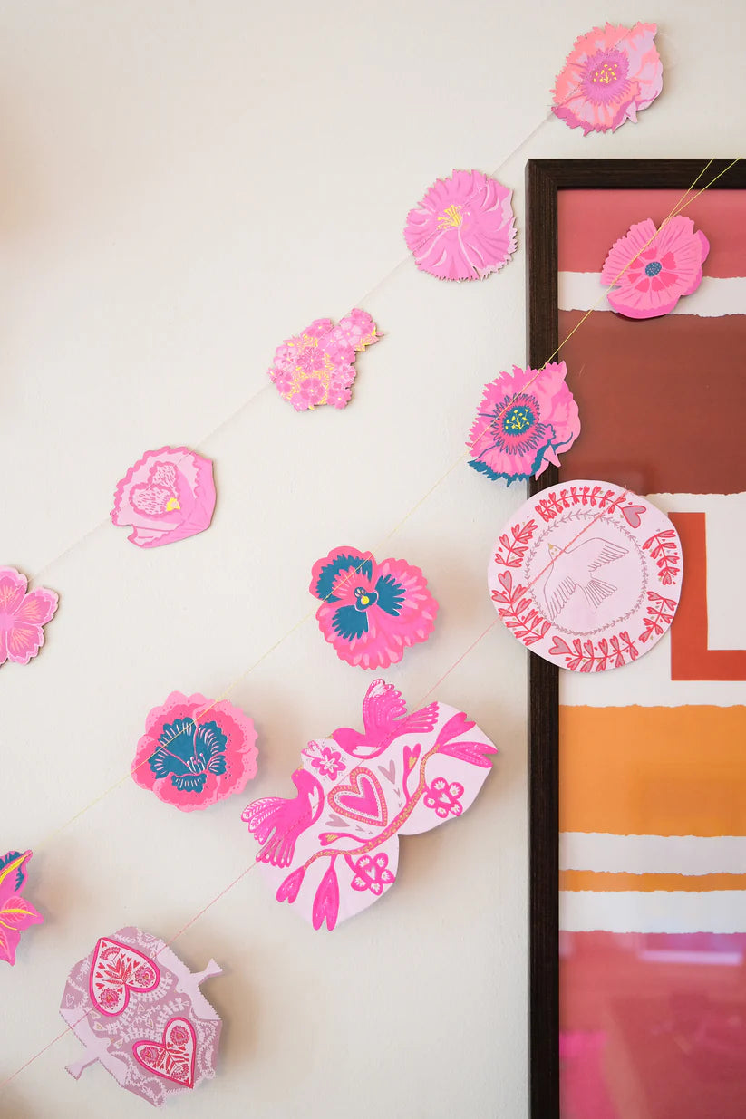 Pink and teal floral paper garland with bird and heart motifs.