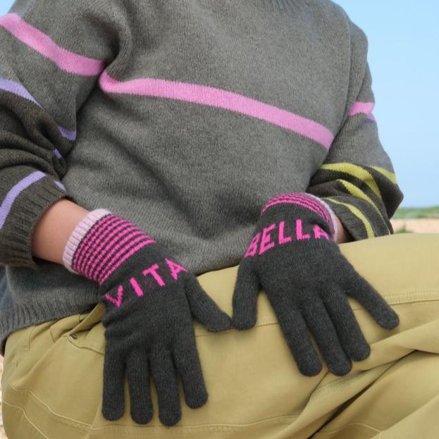 Pair of dark gray cashmere gloves with pink "VITA" and "BELLA" lettering.