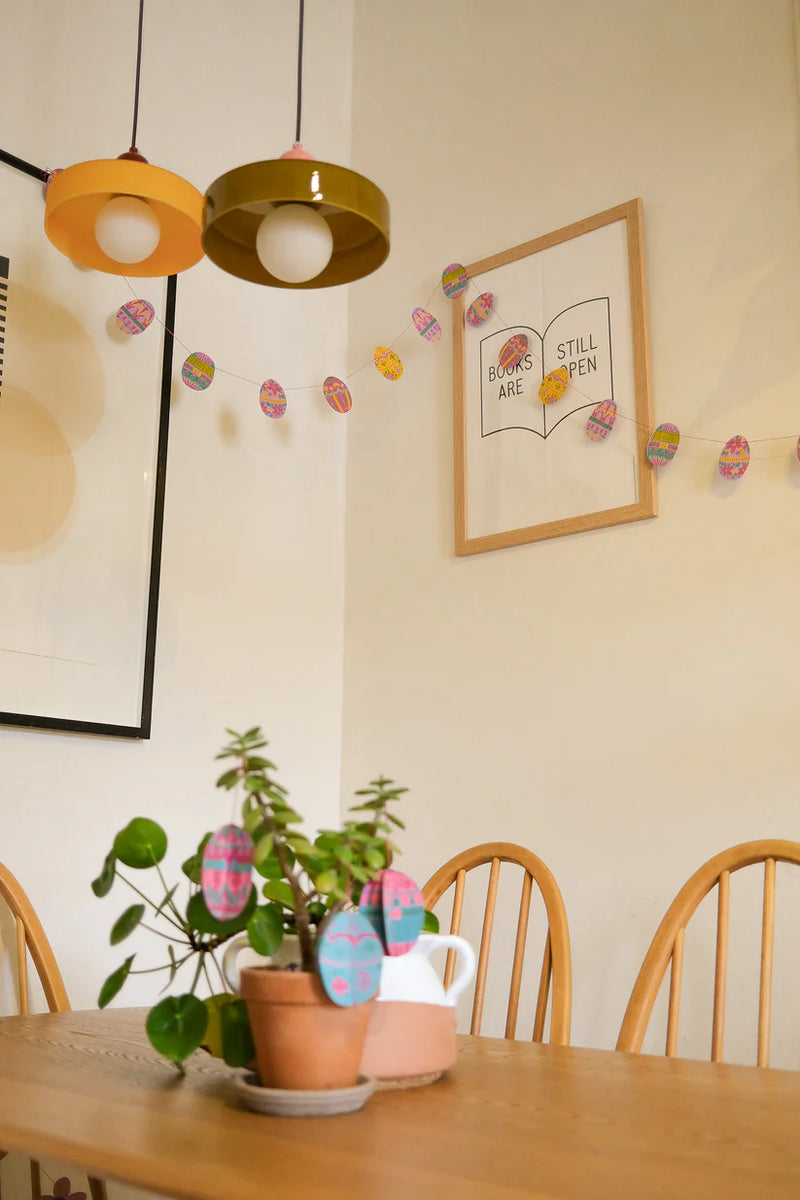 Dining area with wooden table, chairs, and decorative elements on the wall.