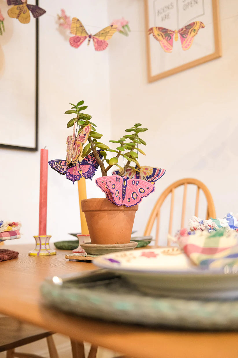 Jade plant in a terracotta pot decorated with colorful paper butterflies.