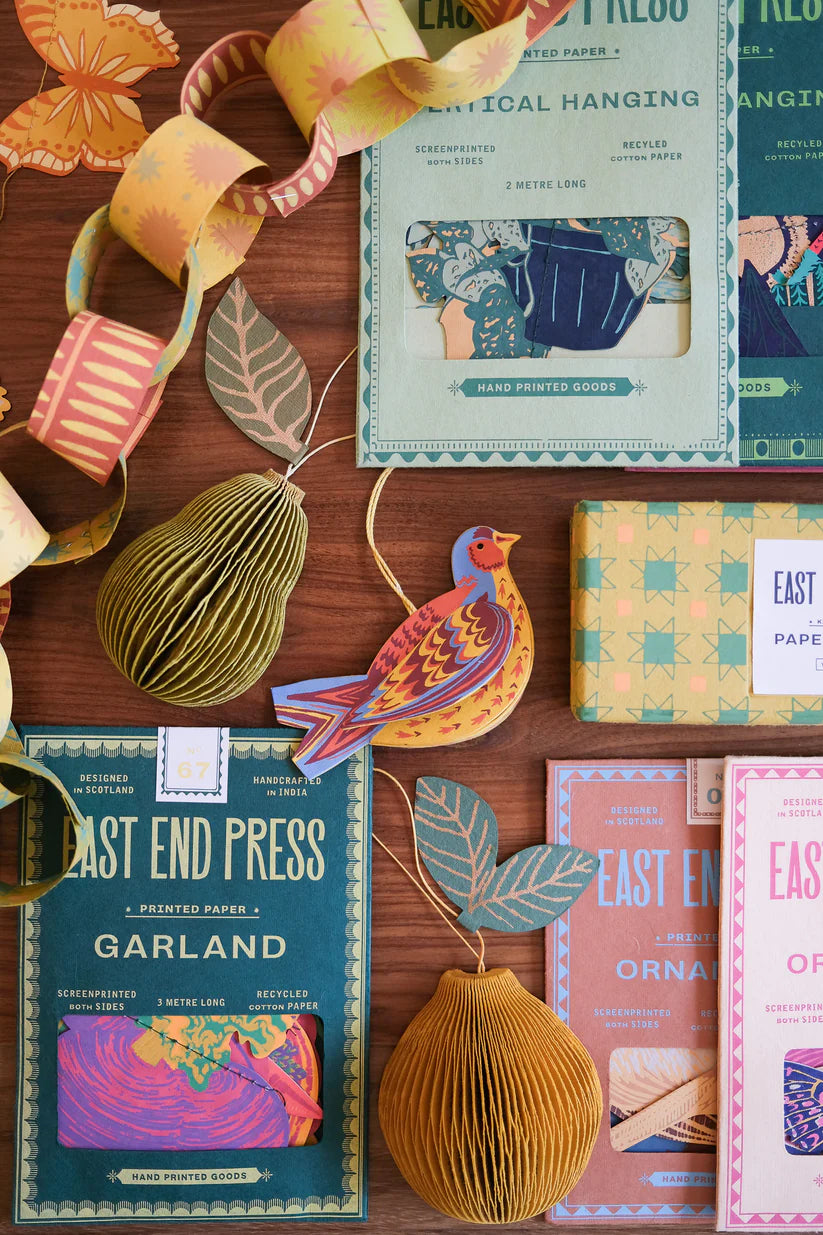 Assortment of East End Press hand-printed paper garlands, ornaments, including pears and a bird, in autumnal colors.