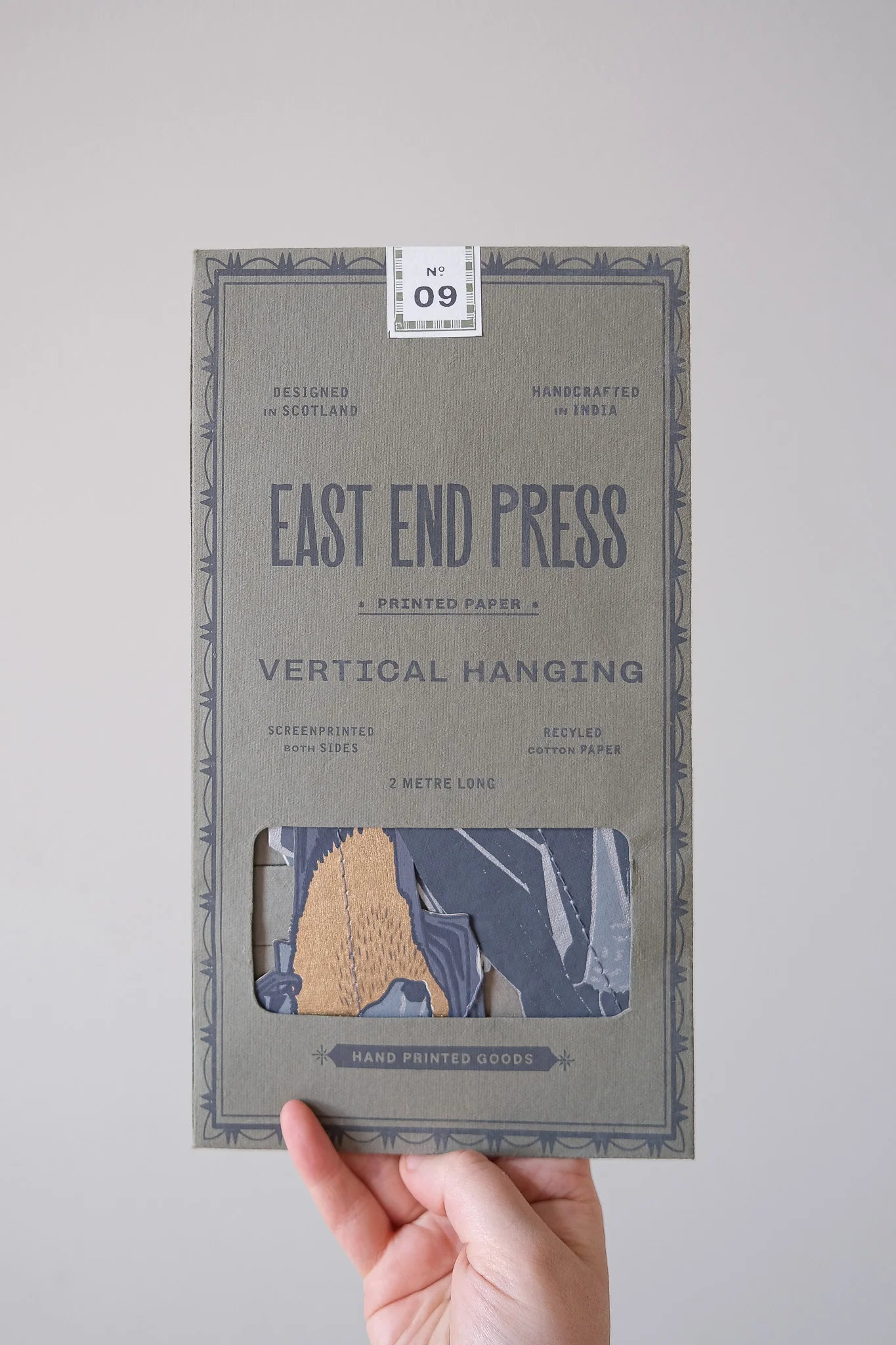 Packaging of East End Press vertical hanging paper with a hand holding it against a plain background
