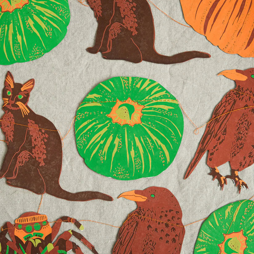 Halloween garland with paper pumpkins, cats, crows, and a spider.  Pumpkins are green and orange; animals are brown.