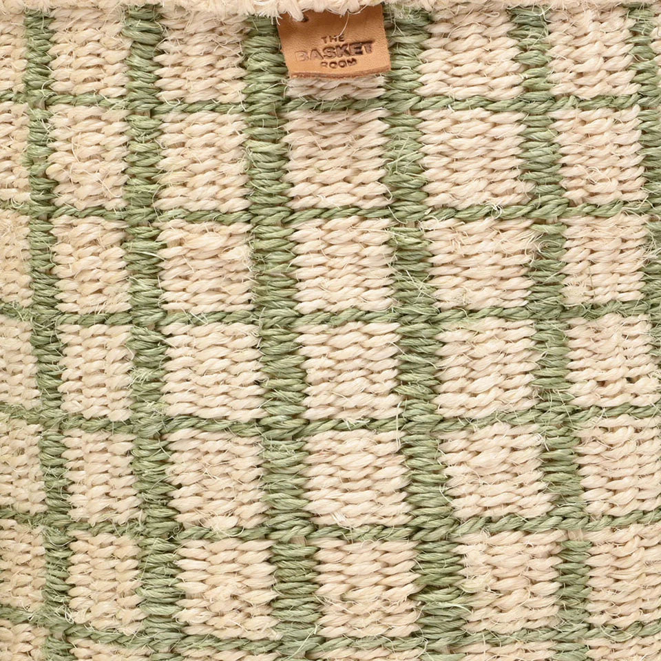 Close-up of a woven basket with a cream and sage green checkered pattern.