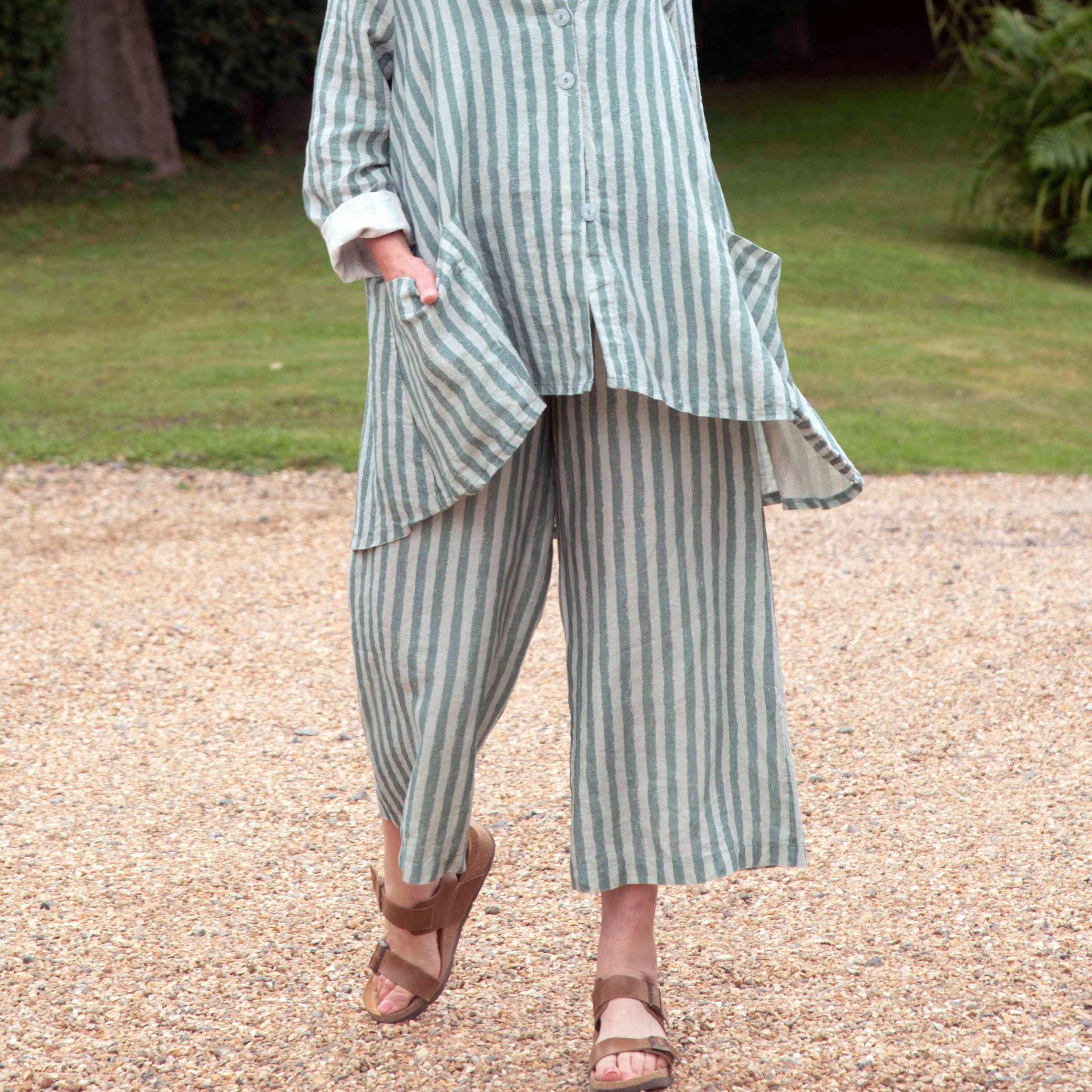 A woman's light green and white striped linen pantsuit.  The wide-leg pants and oversized shirt have patch pockets.