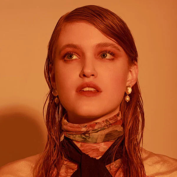 Person with wet hair wearing a dark scarf against a warm-toned background