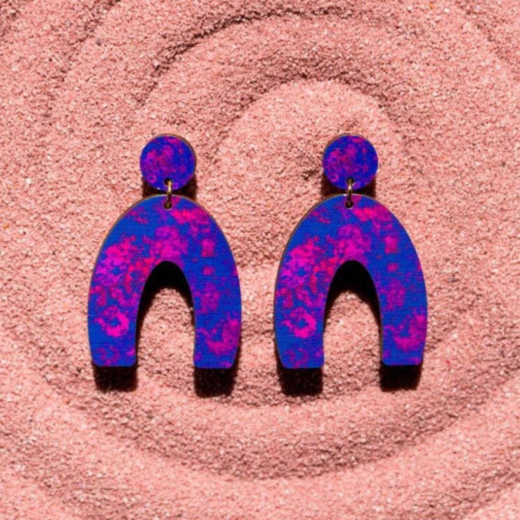 Pair of purple and pink arch-shaped wooden earrings with speckled paint effect.