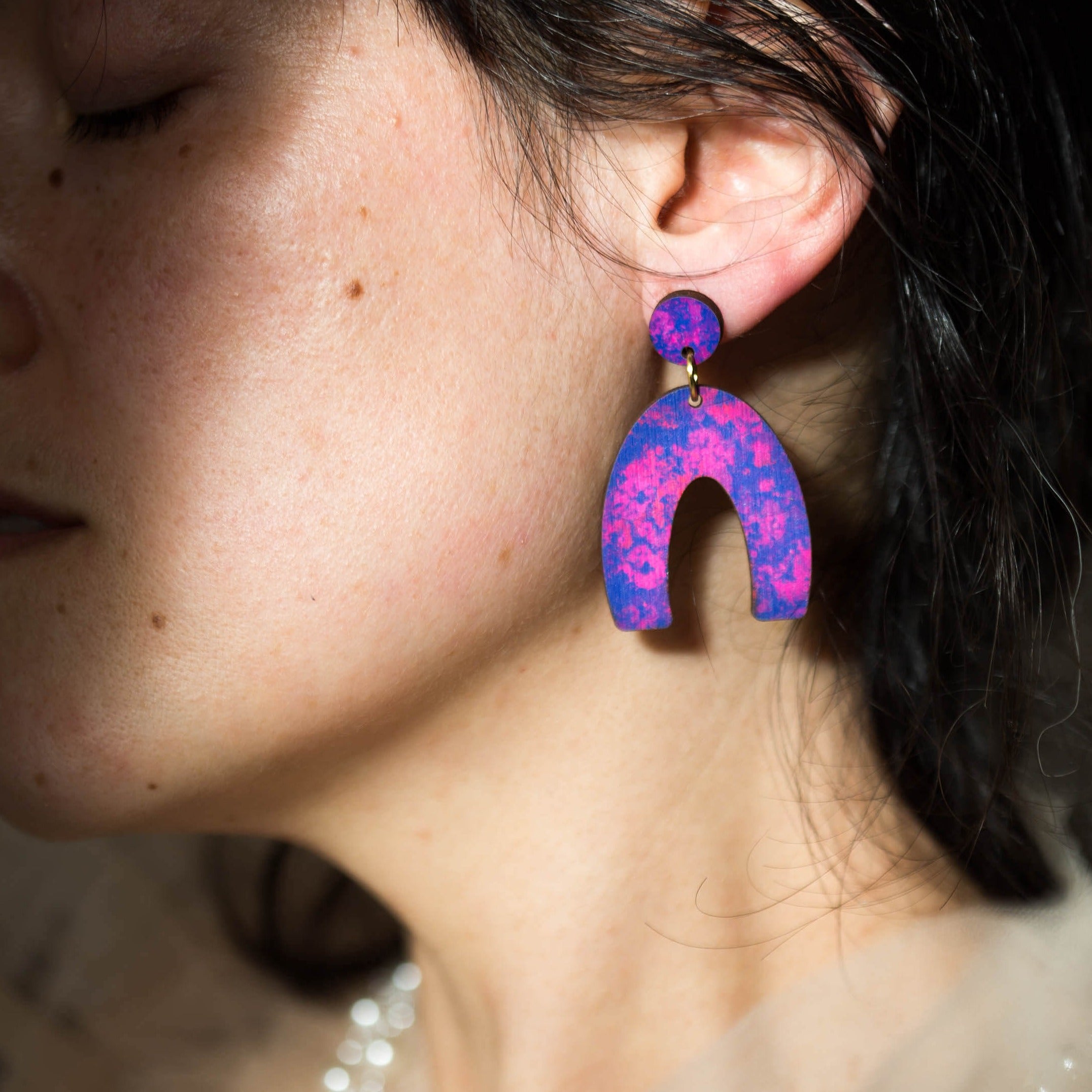 Purple and pink marbled horseshoe-shaped earrings with gold connectors.