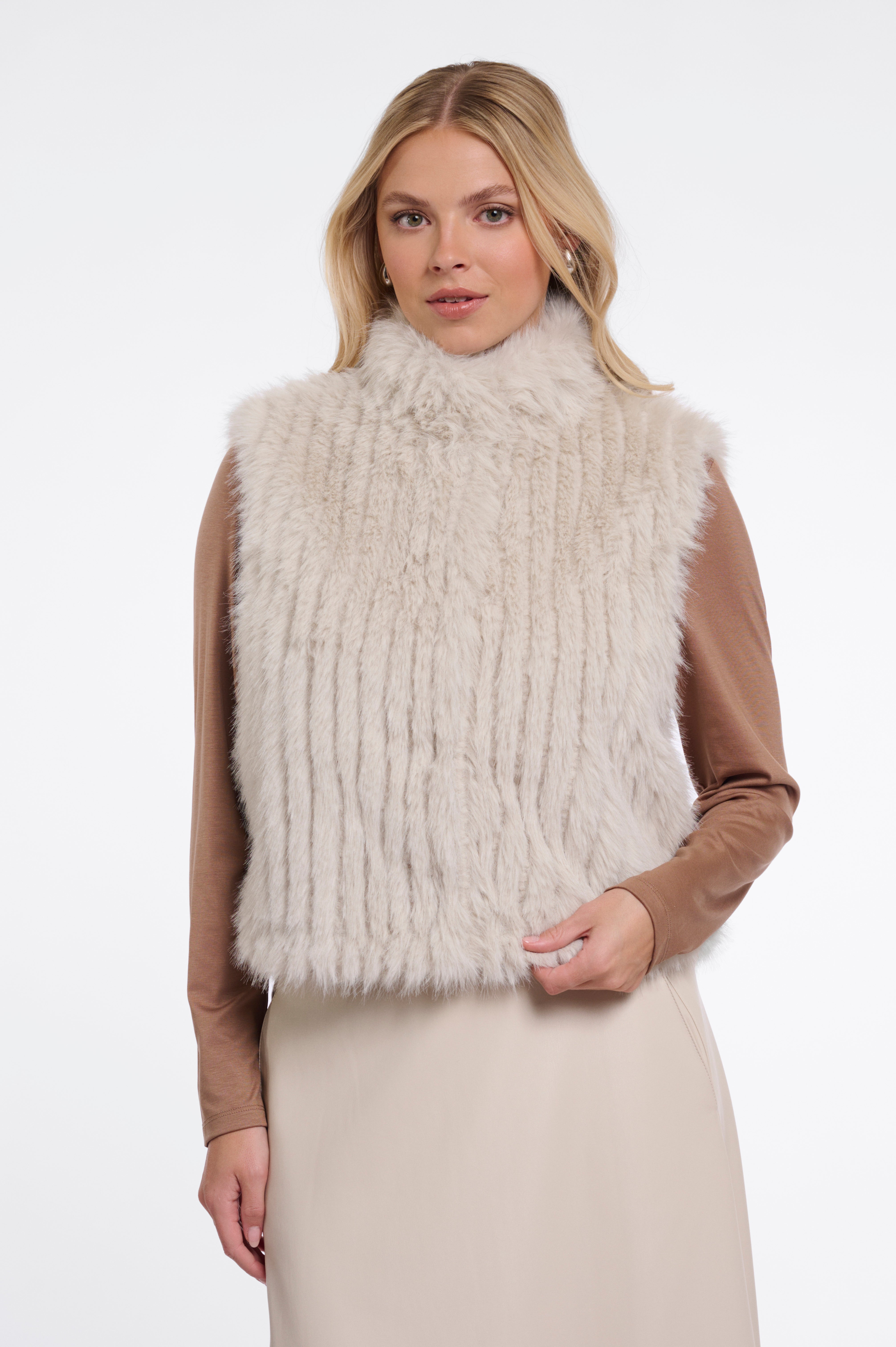 Woman wearing a beige fur vest on a white background