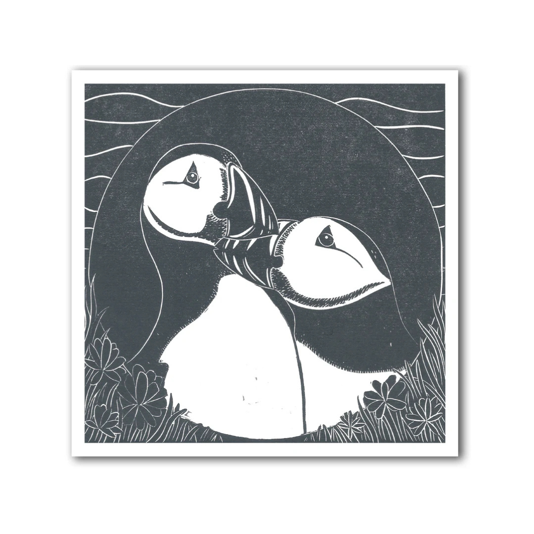 Black and white illustration of a puffin on a dark background with floral elements.