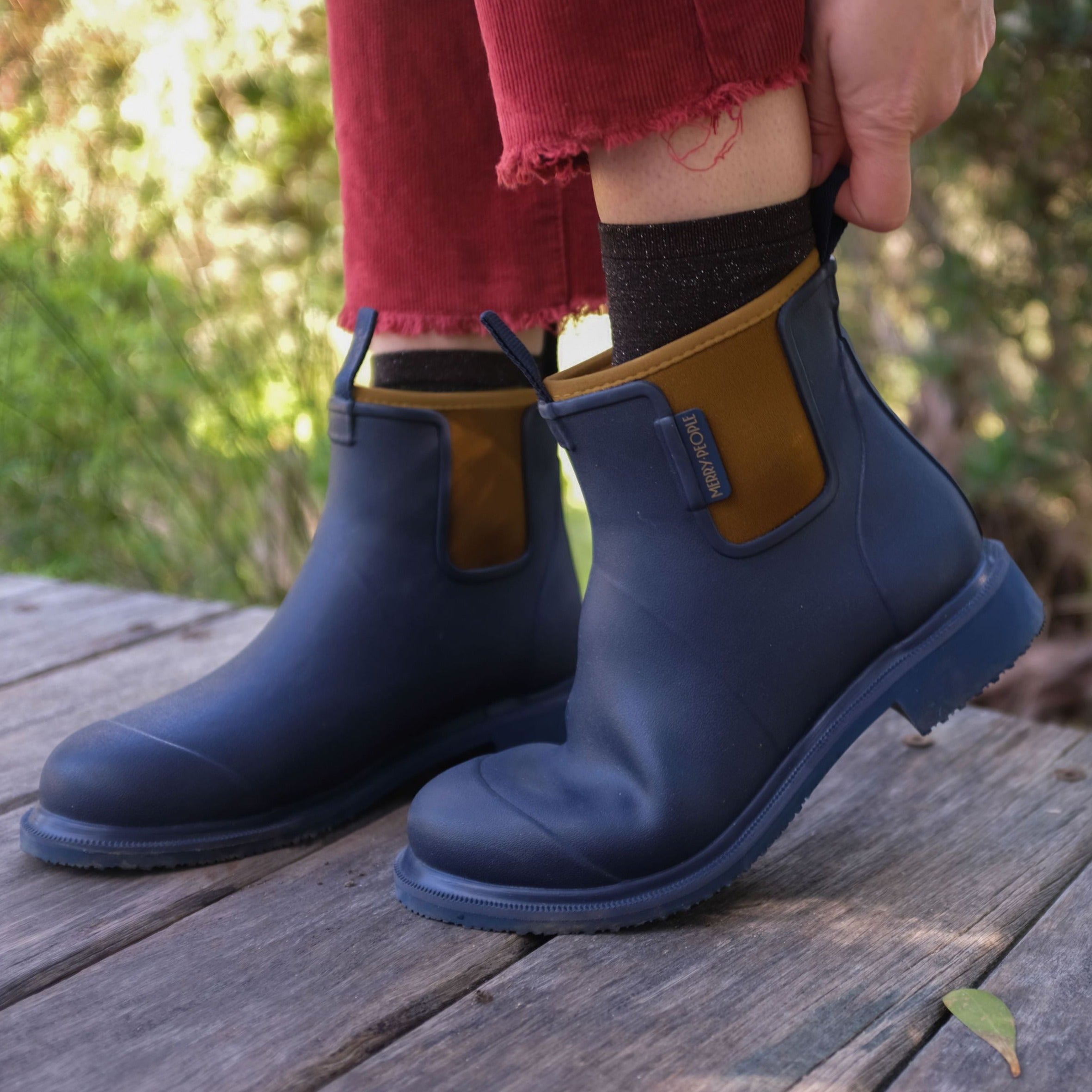 Pair of navy blue Merry People rain boots with tan colored back accents.  The boots have a slightly chunky sole.