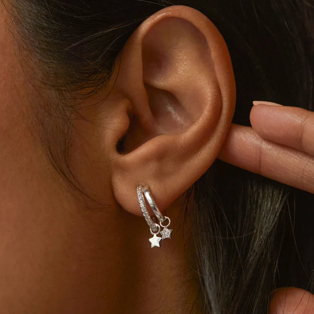Silver hoop earrings with small, sparkling star charms.