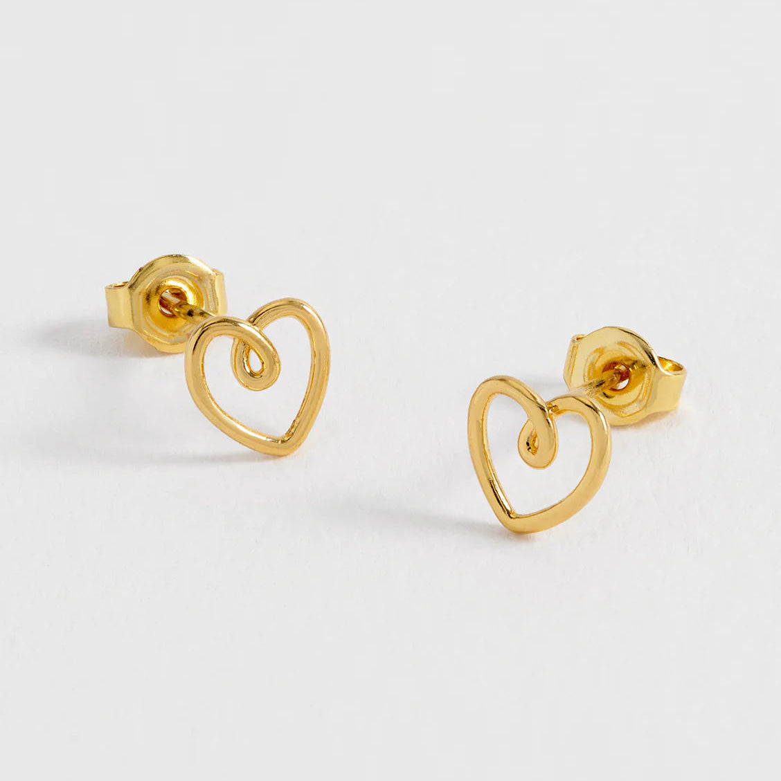 Gold heart-shaped stud earrings on a light gray background