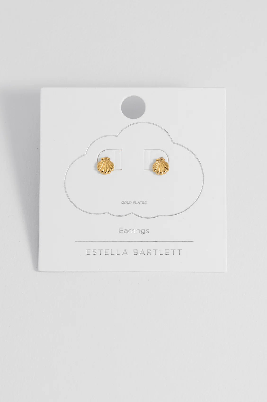 A pair of gold shell stud earrings displayed on a white cloud-shaped card labeled 'ESTELLA BARTLETT' against a light gray background.