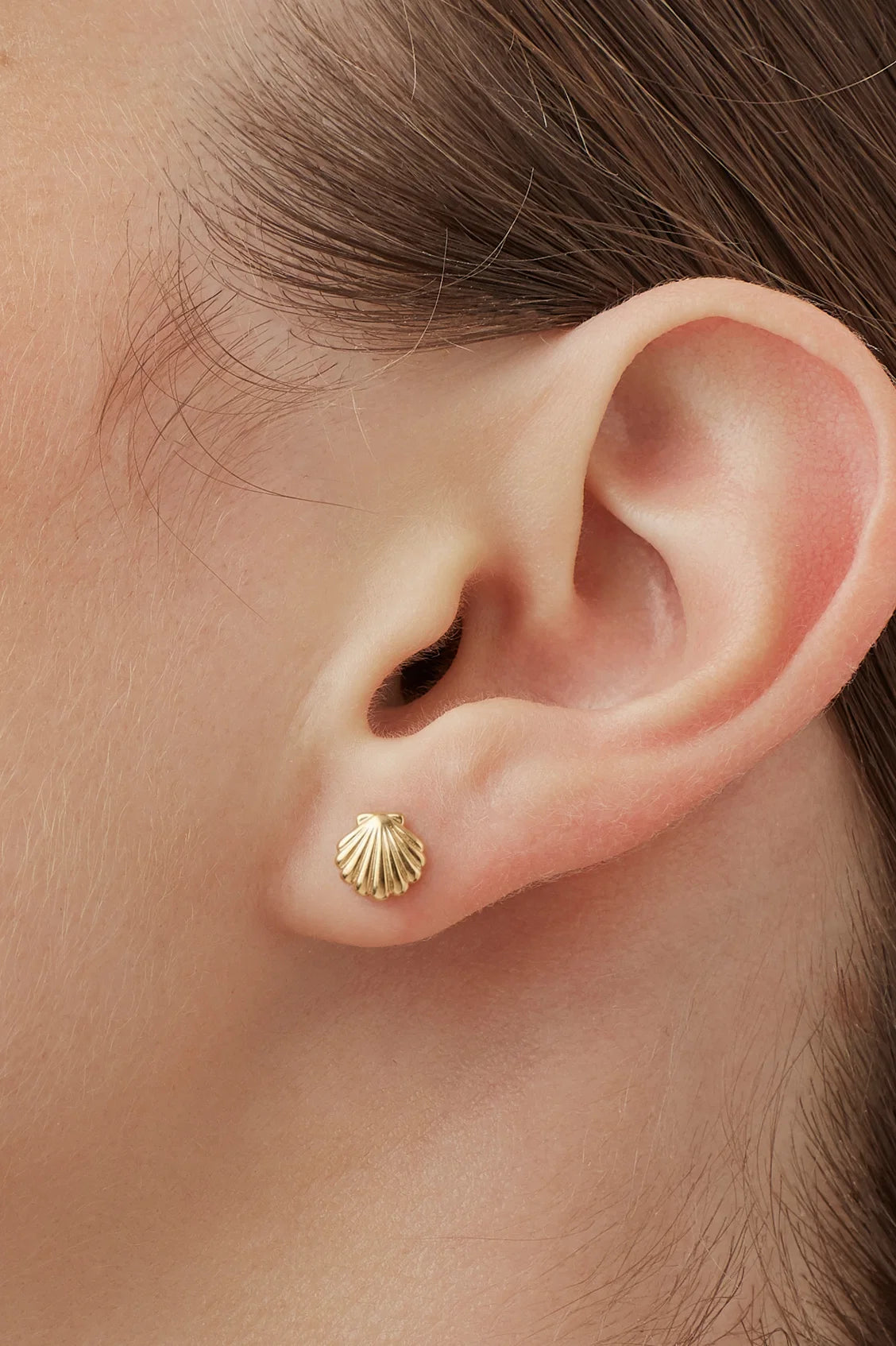Gold earring worn on a person's ear