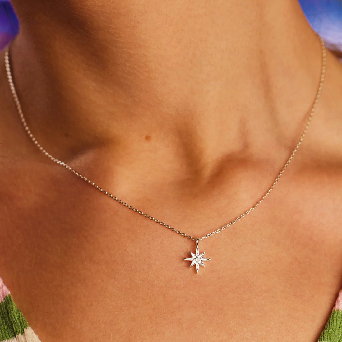 Silver chain necklace with a small, sparkling starburst pendant.