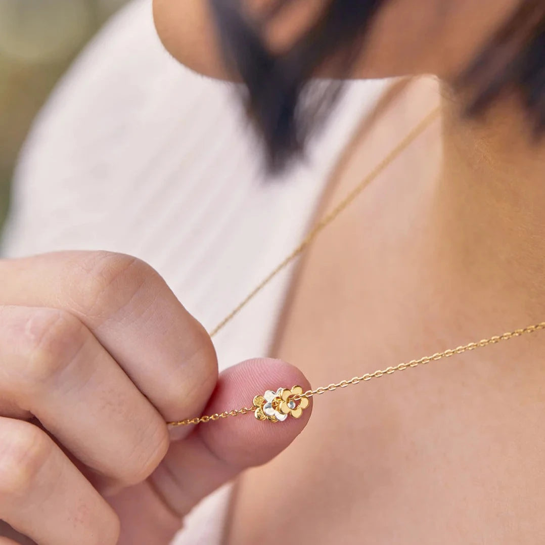 Gold necklace featuring a delicate cluster of small flowers as a pendant.