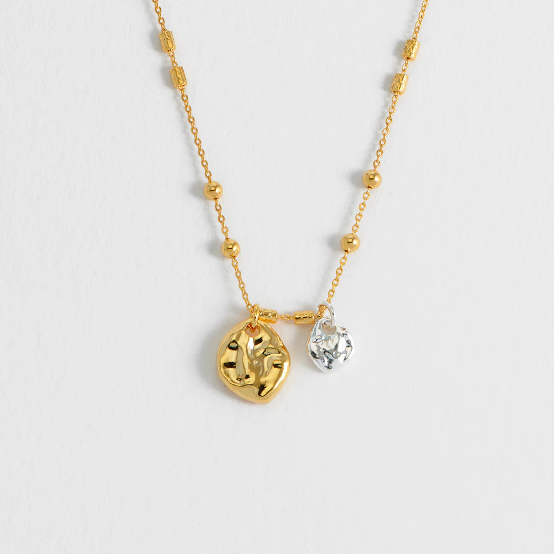 Gold necklace with beaded chain and two textured disc pendants; one gold, one silver.