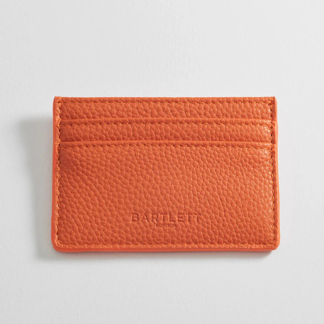 Orange leather card holder with three card slots and "Bartlett London" embossed on the front.