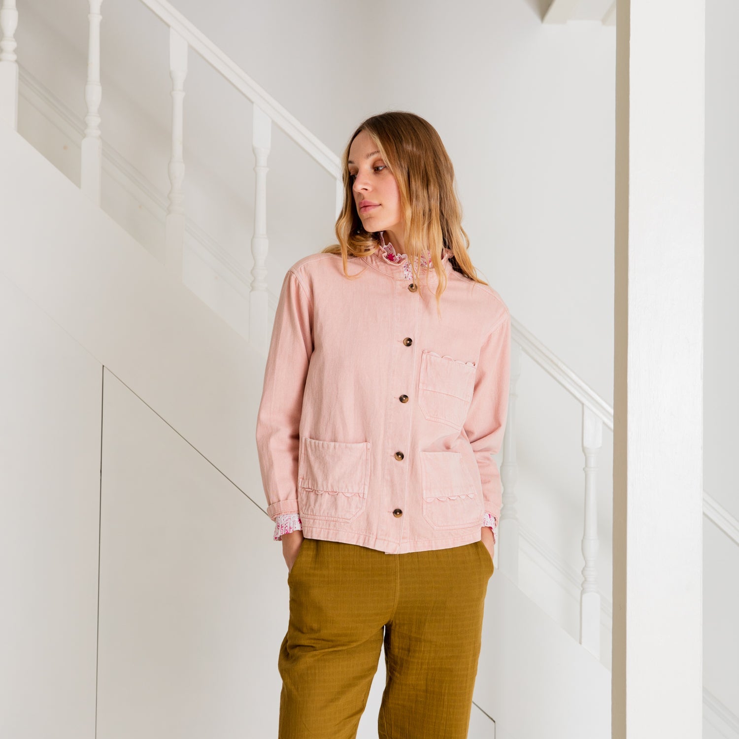 Pink button-up jacket with scalloped detailing and patch pockets, worn with mustard-colored pants.