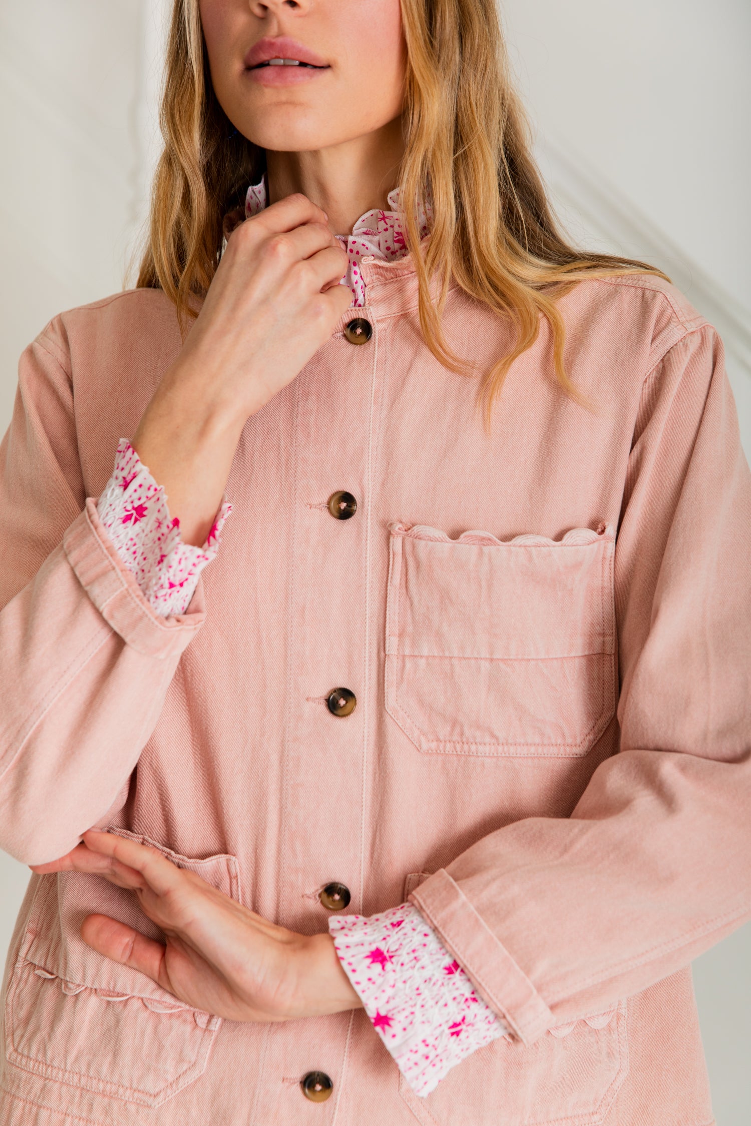 Dusty rose denim jacket with scalloped pockets and button front closure.