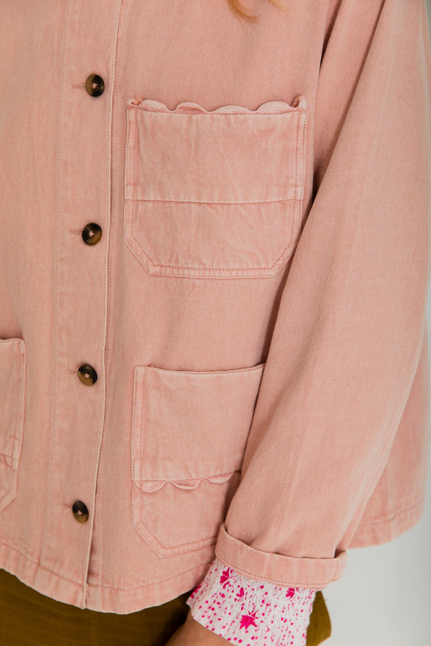 Dusty rose denim jacket with scalloped pocket detailing and button closure.