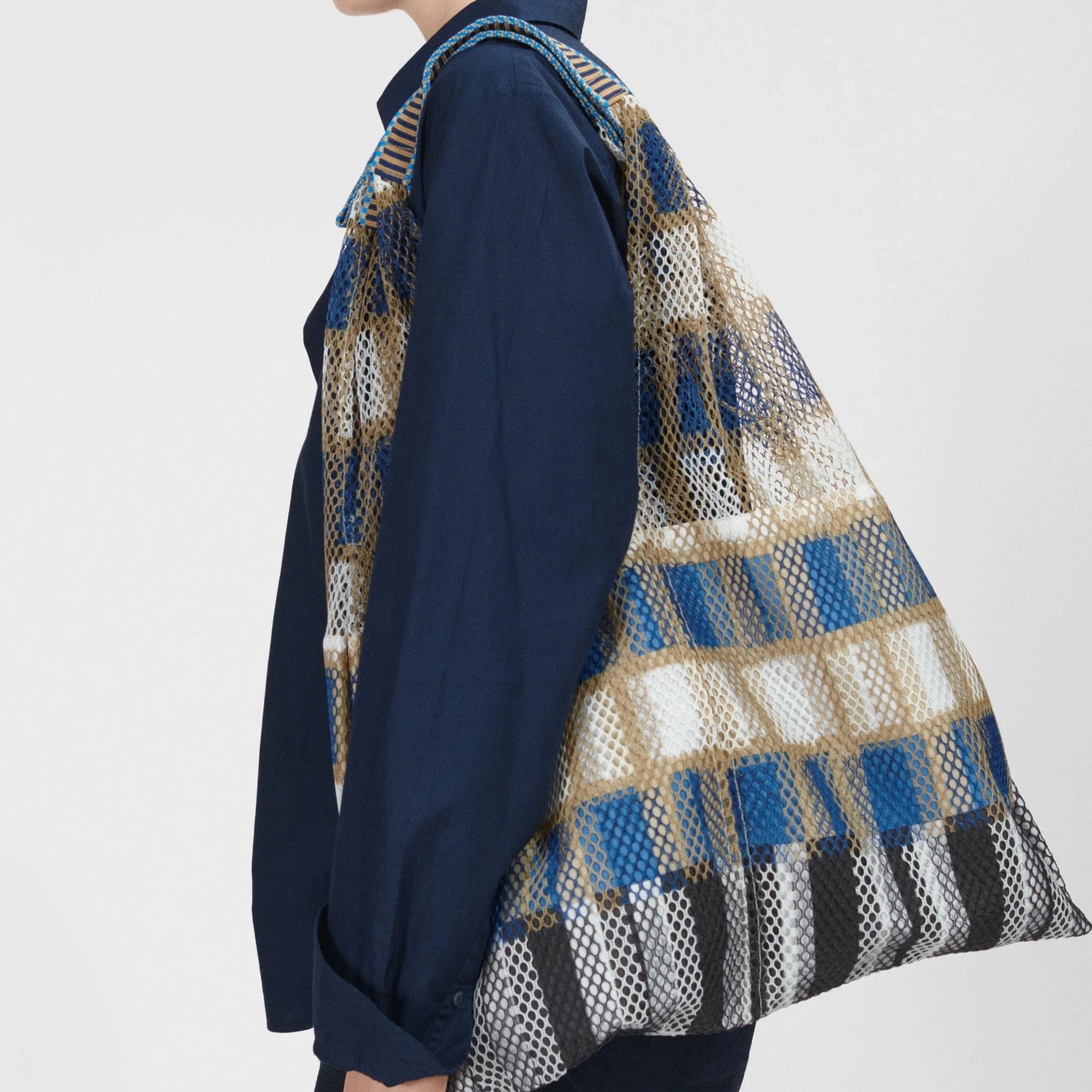 Large mesh tote bag with a blue, beige, and white plaid pattern.  The bag has woven straps and a slightly slouchy shape.