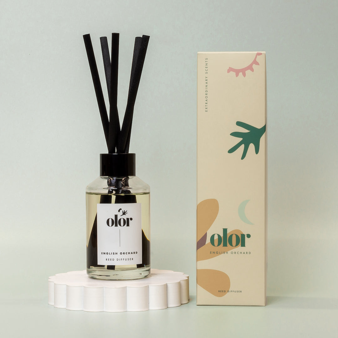Olor English Orchard reed diffuser in a clear glass bottle with black reeds and matching box.