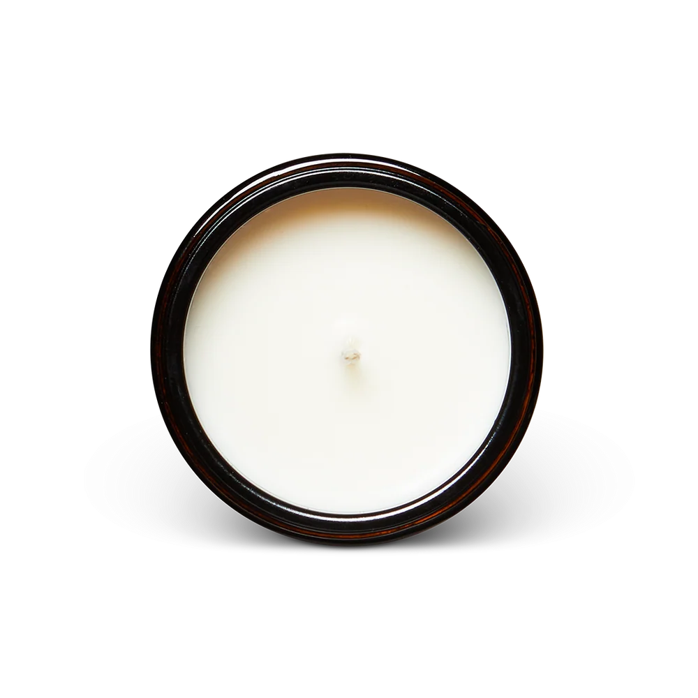 A top-down view of a round candle in a dark brown wood-grain container with white wax, centered on a clean white background.