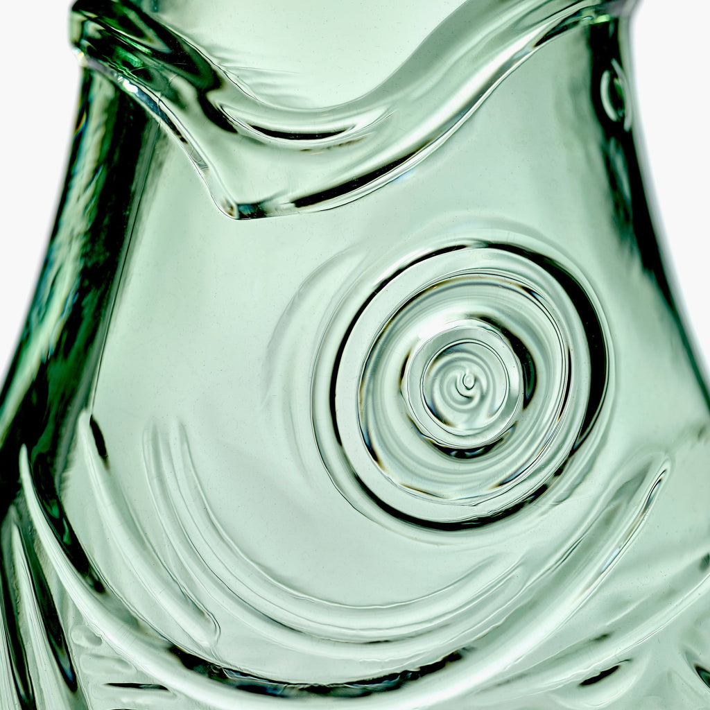 close up of a green, pressed glass carafe, from the Fish & Fish tableware collection, by Italian designer Paola Navone, for Belgian design brand Serax.