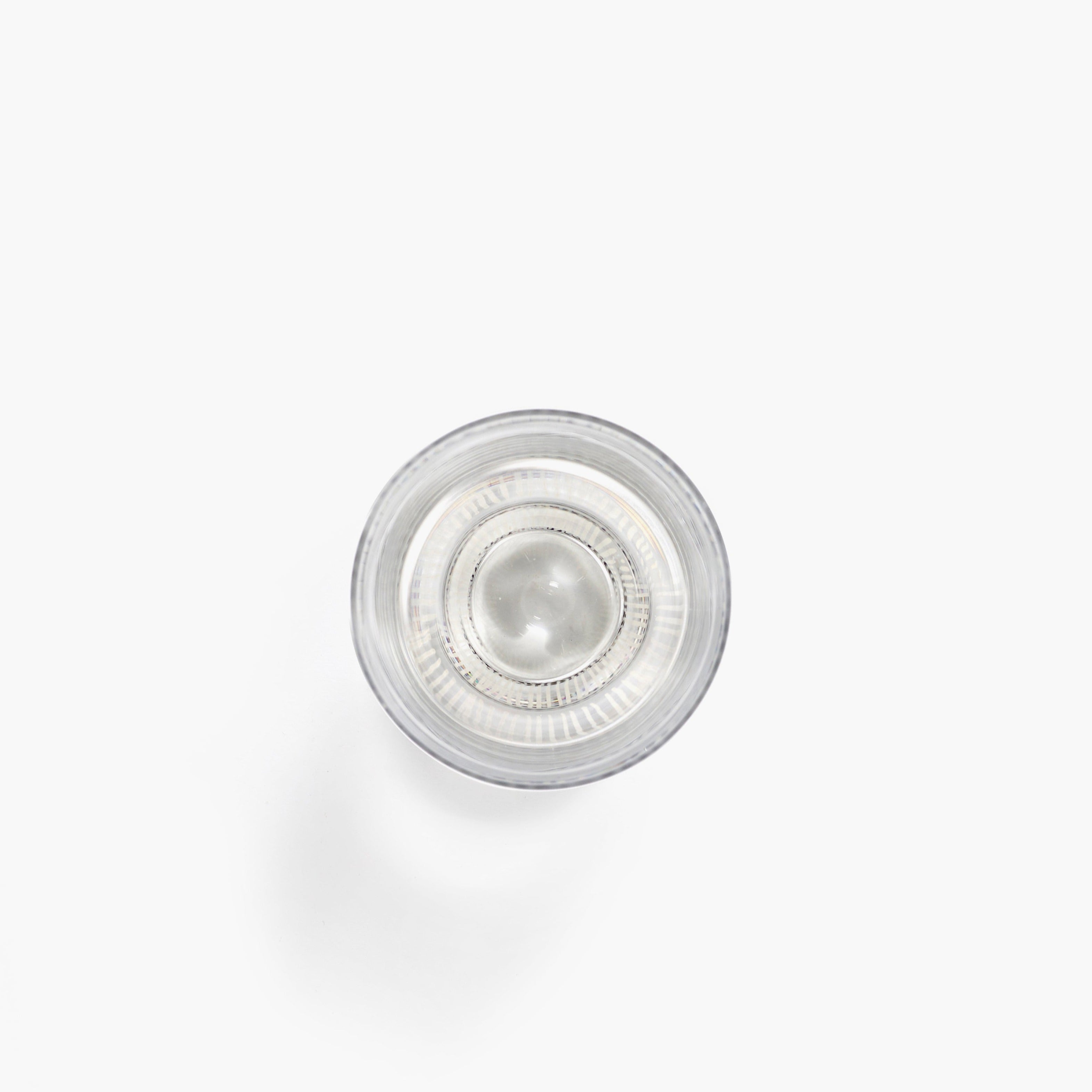 Overhead view of a clear glass filled with water, showing subtle concentric rings within the liquid.