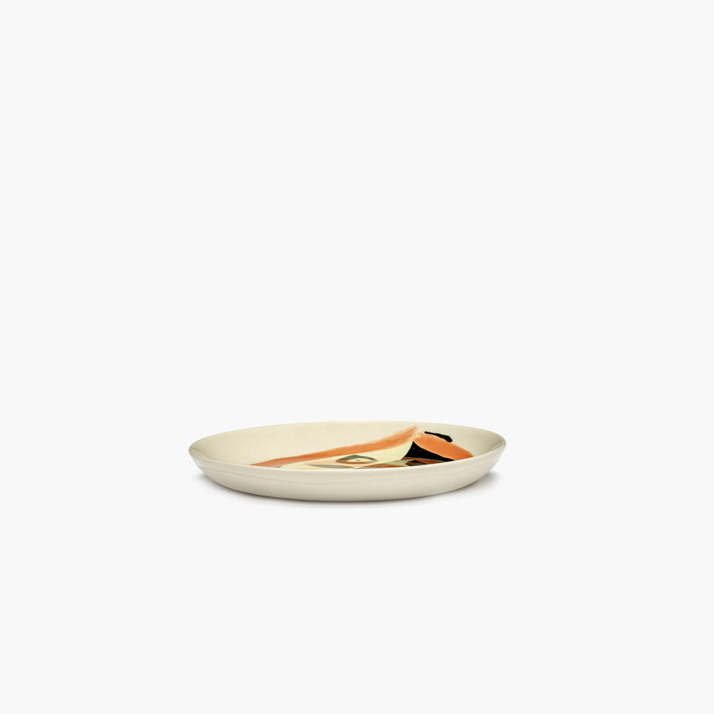 plate with a painting of a face in black, orange and green, designed by British-Israeli chef Yotam Ottolenghi, for Belgian design brand Serax.