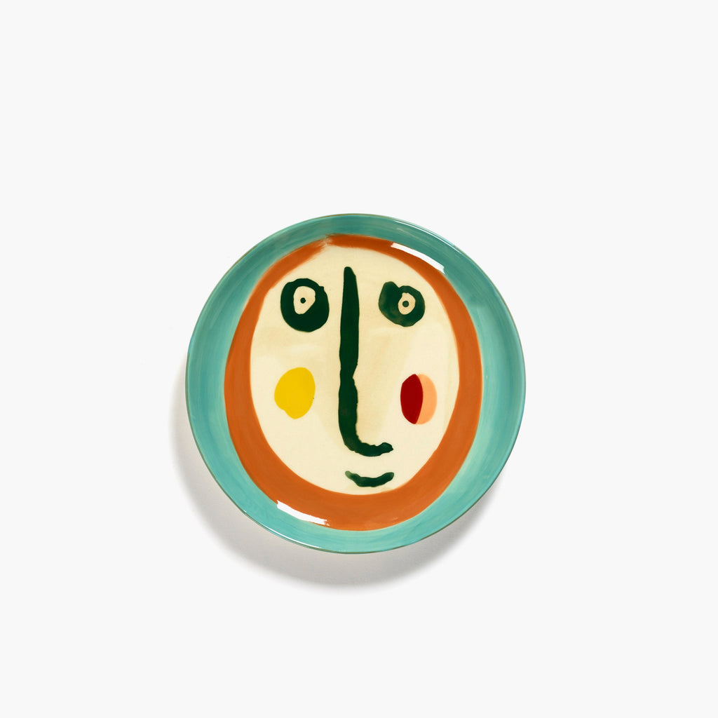 cream coloured plate with a painting of a face in deep blue, orange and green, designed by British-Israeli chef Yotam Ottolenghi, for Belgian design brand Serax.