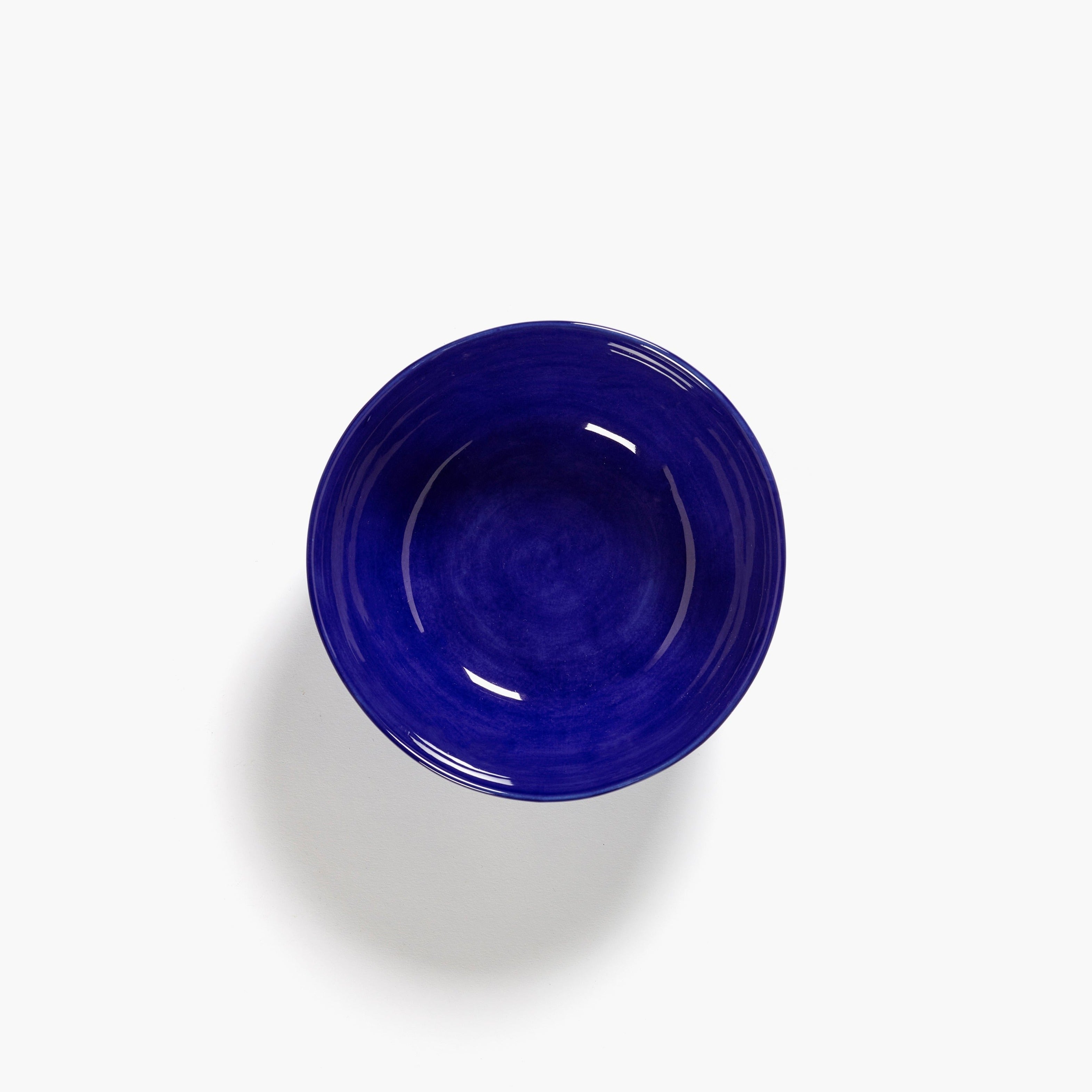 A dark blue, round bowl viewed from above, showing subtle variations in shade and texture.