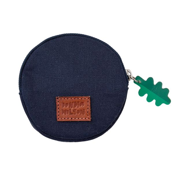 Navy blue round pouch with a brown leather patch and green leaf charm on a white background