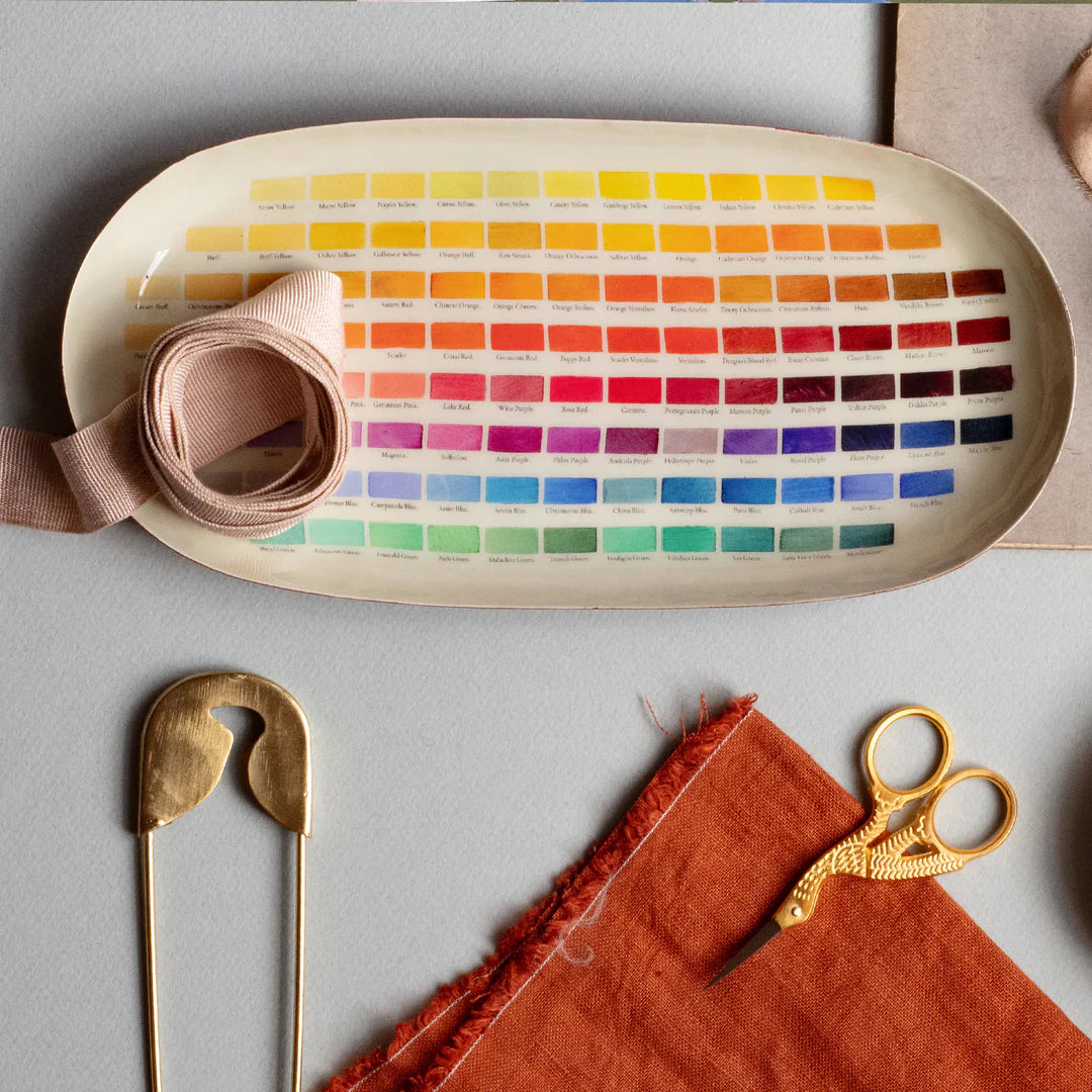 Color swatch chart with fabric samples and sewing tools on a gray surface