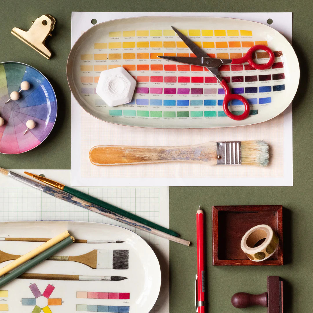 Art supplies including brushes, scissors, and a color swatch on a green surface